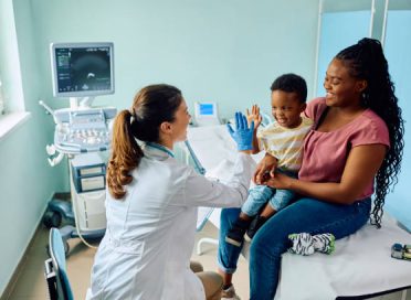 Happy African American boy giving high five to his pediatrician after medical examination at doctor's office.