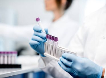 Laboratory assistant putting test tubes into the holder, Close-up view focused on the tubes