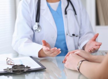 Close up of a doctor and  patient hands discussing something while sitting at the table . Medicine and health care concept